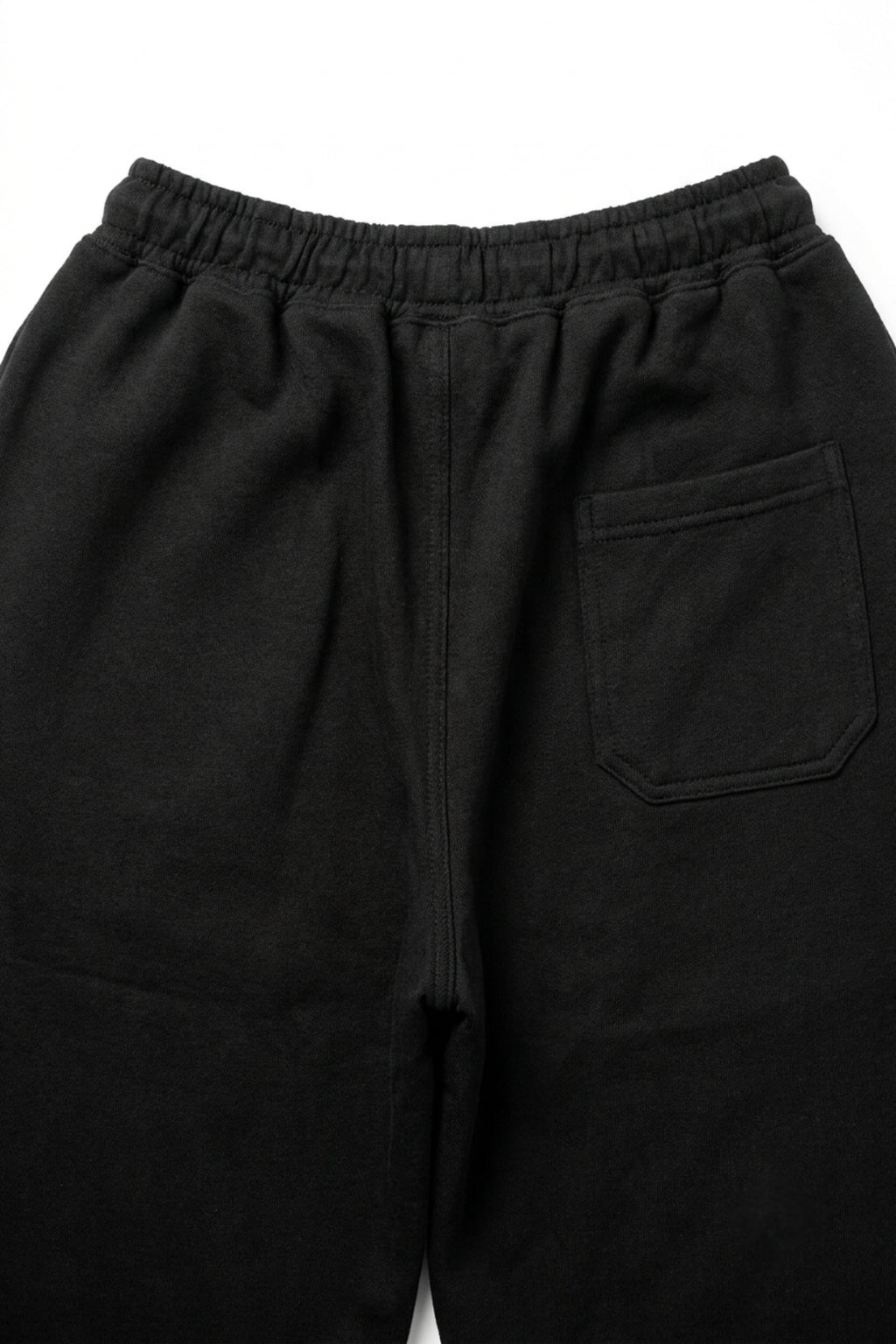 Macro view of the rear pocket and loopback French terry knit texture on the Deep Black lounge trousers.