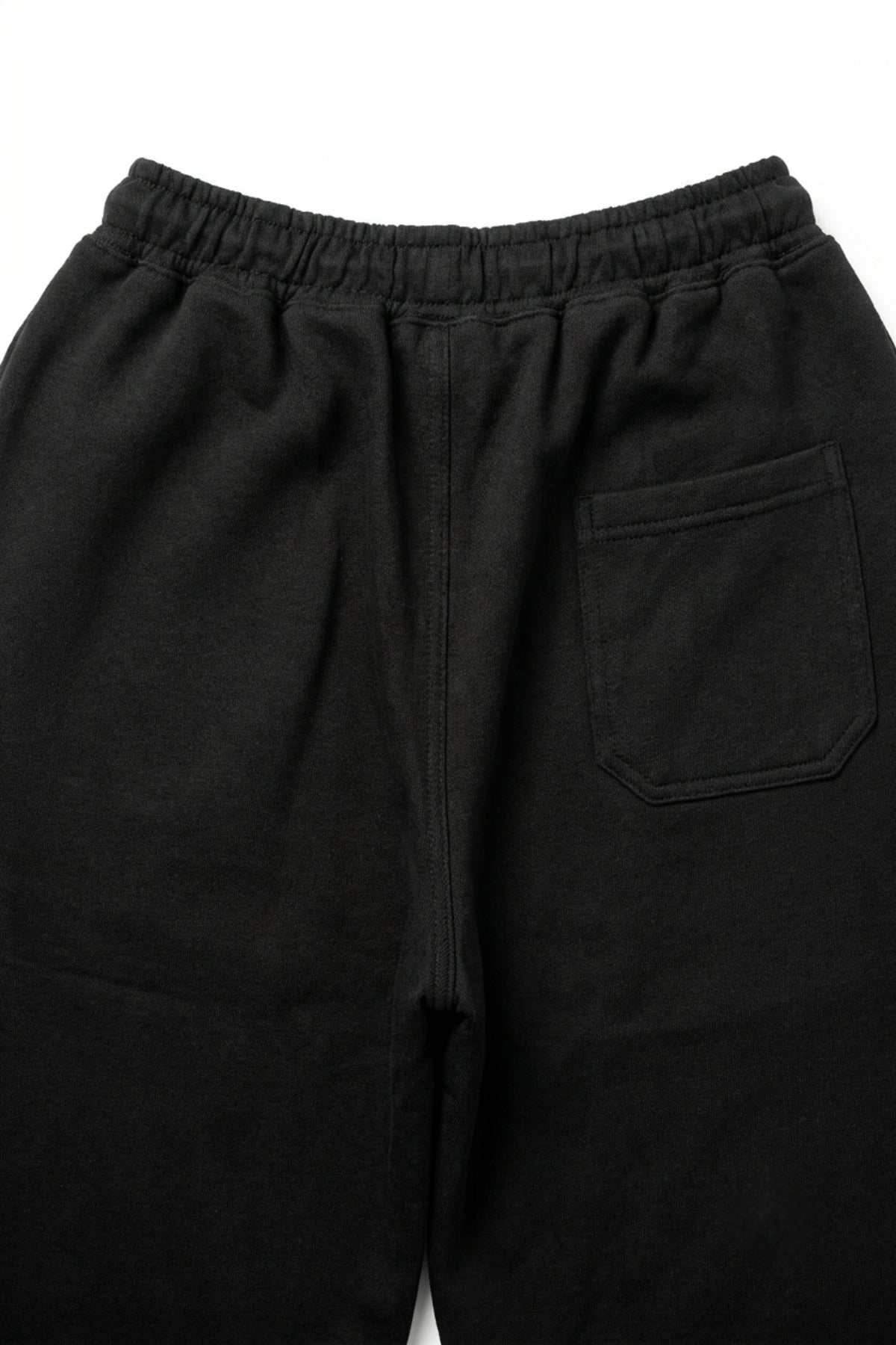Macro view of the rear pocket and loopback French terry knit texture on the Deep Black lounge trousers.