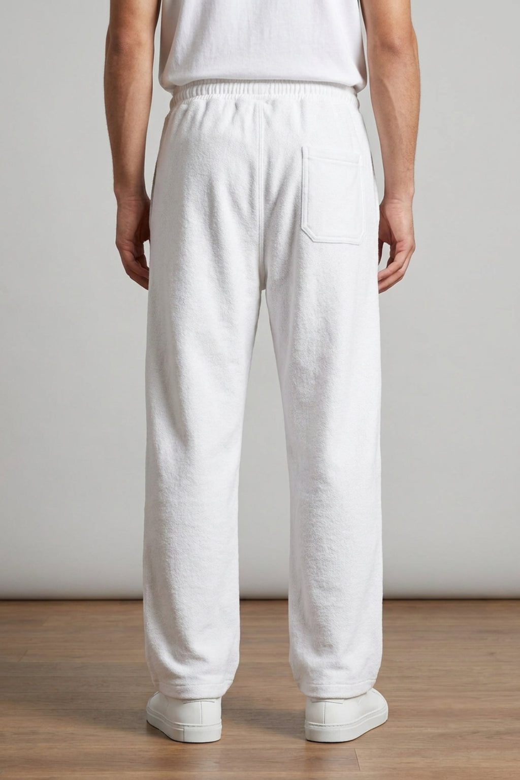 Rear view of a male model wearing Classic Lounge Lightweight Terry Trousers in Optic White, showcasing the relaxed baggy drape and rear pocket detail.