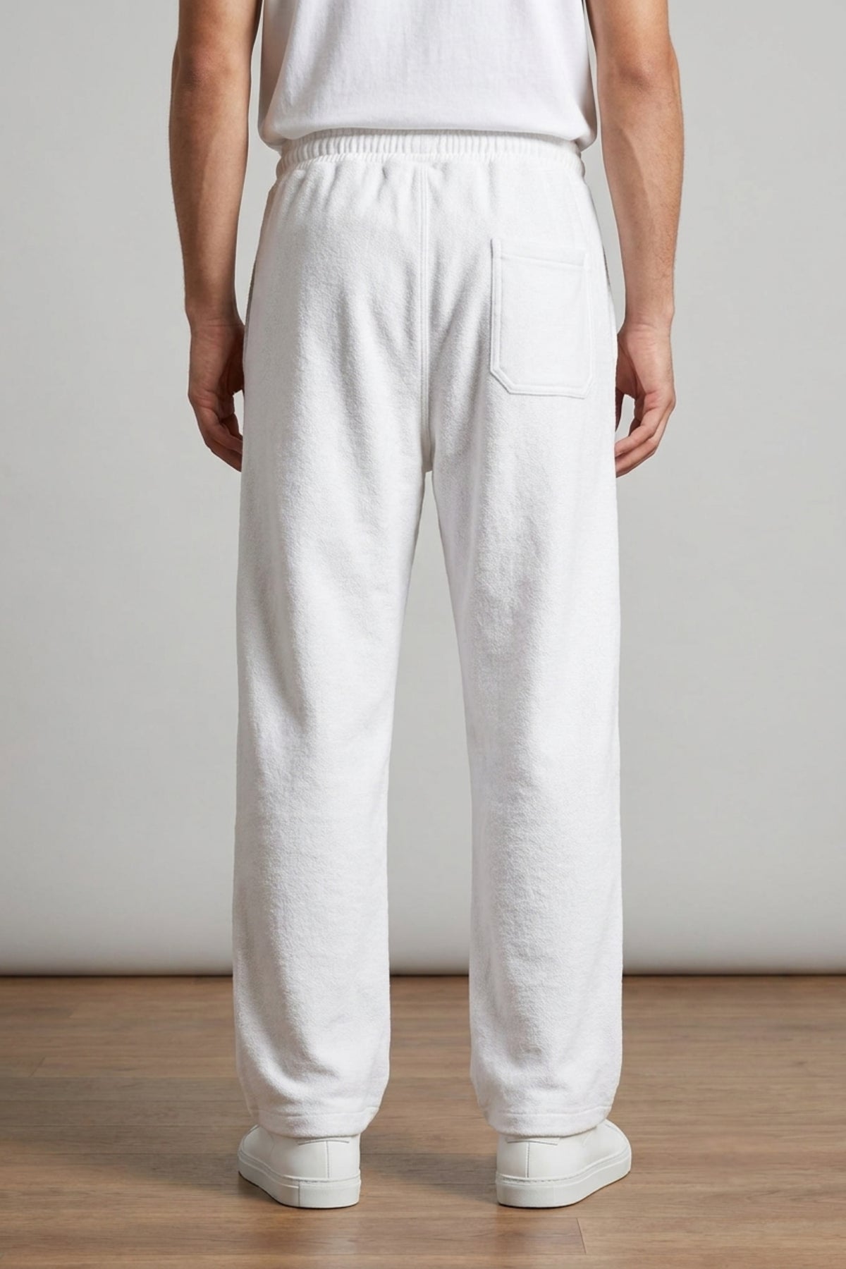 Rear view of a male model wearing Classic Lounge Lightweight Terry Trousers in Optic White, showcasing the relaxed baggy drape and rear pocket detail.