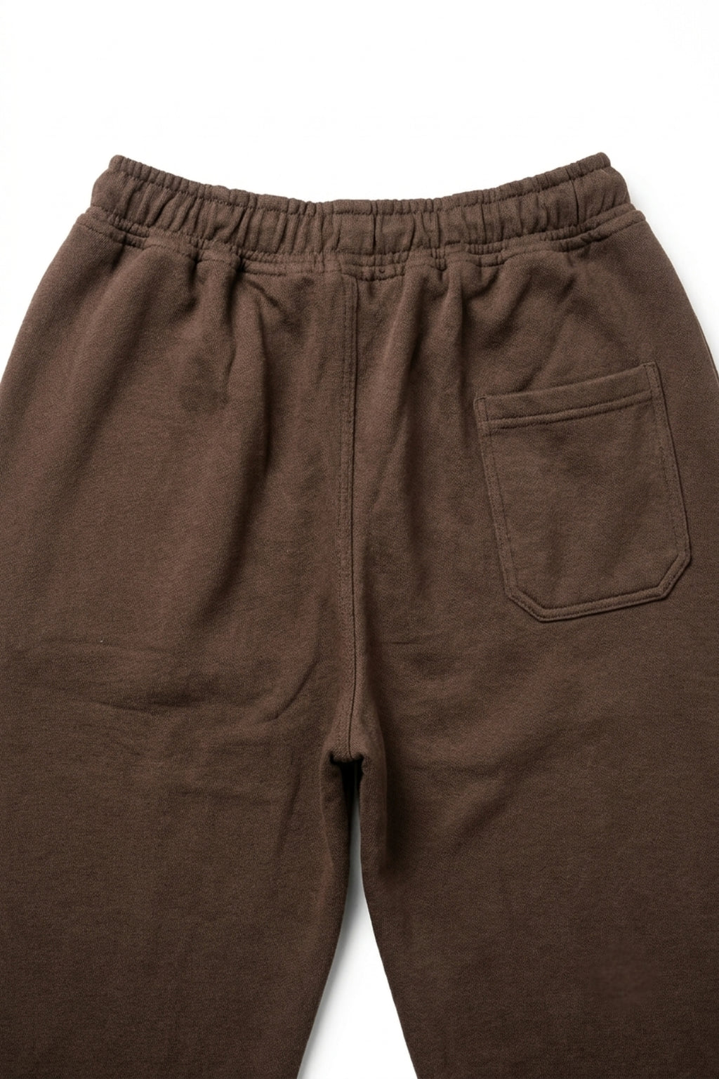 Detailed macro view of the rear pocket and premium loopback French terry cotton fabric texture on dark brown lounge trousers.