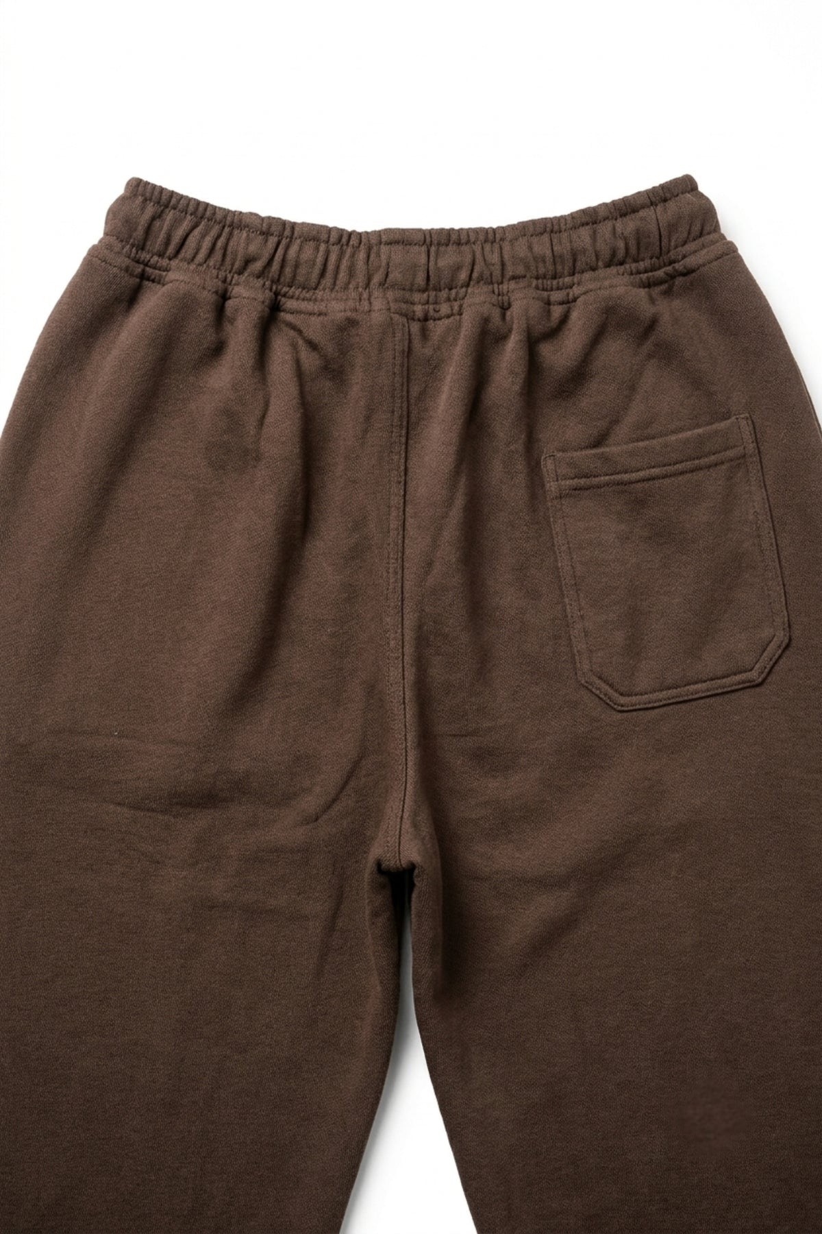 Detailed macro view of the rear pocket and premium loopback French terry cotton fabric texture on dark brown lounge trousers.