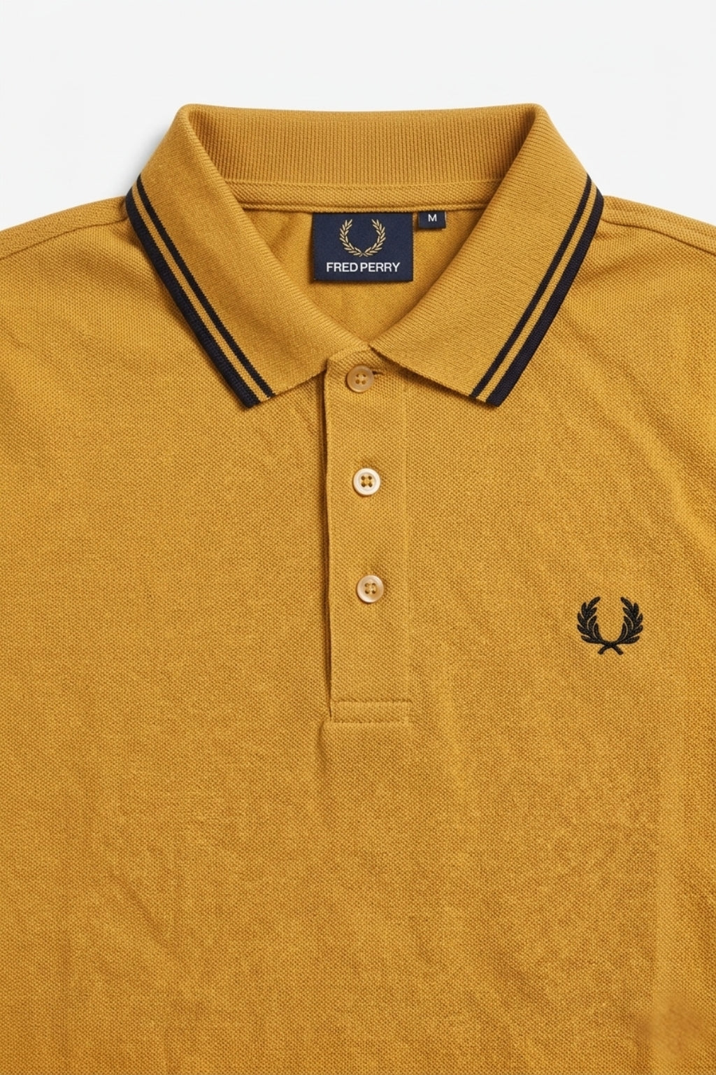 Close-up detail of Eliteez Heritage Twin-Tip Polo - Mustard premium pique and embroidered logo.
