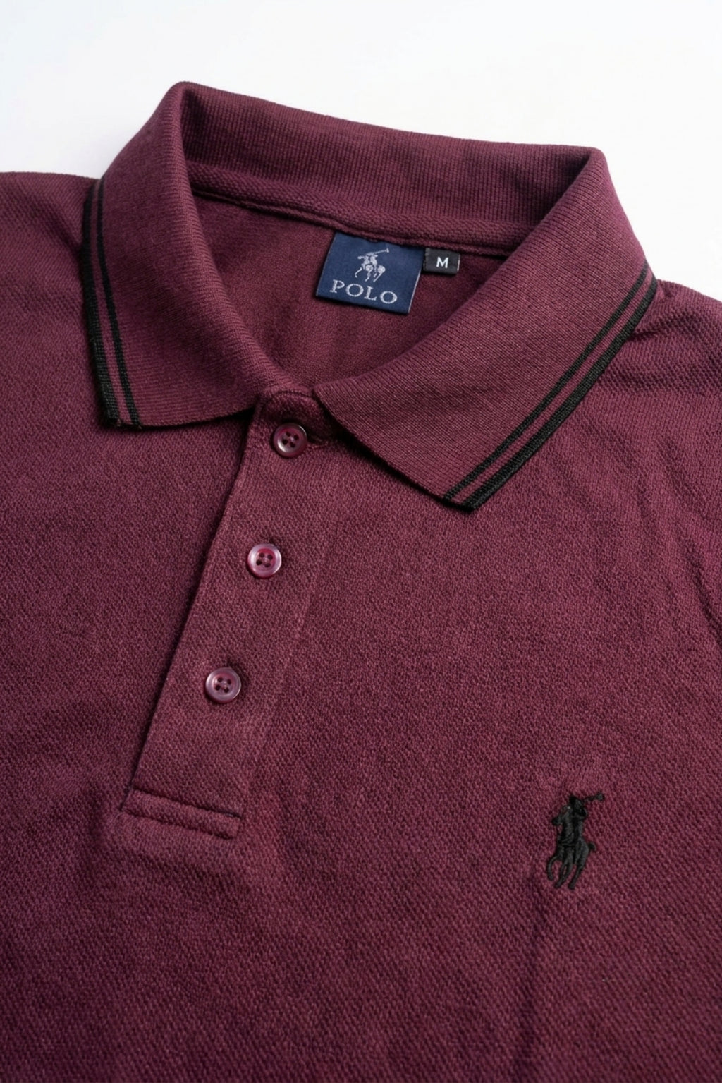 Close-up detail of Eliteez Piqué Polo Rider Burgundy embroidered logo